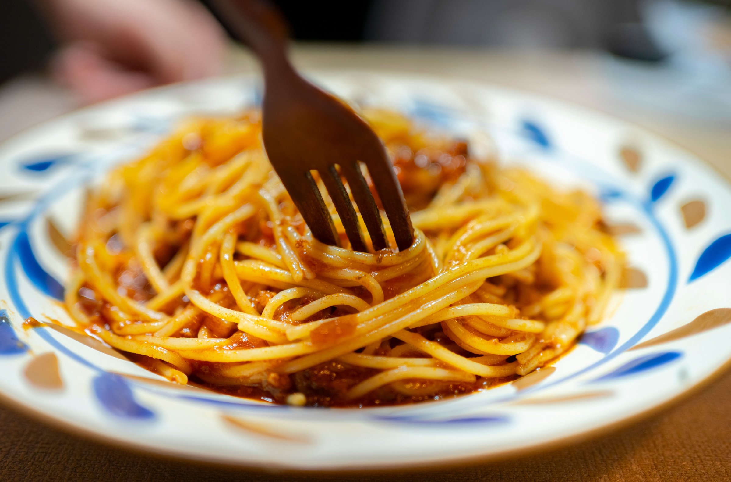 Fork twirling spaghetti in a patterned bowl