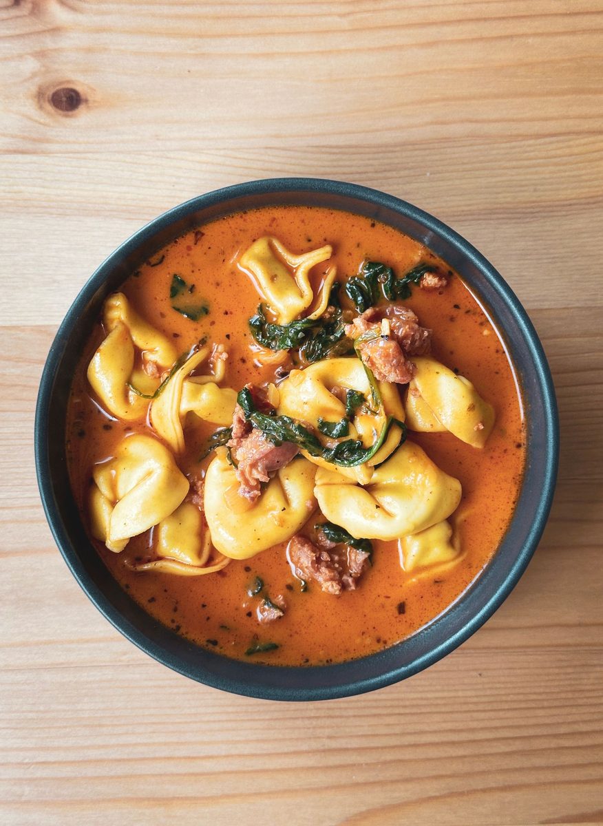 A bowl of agnolotti pasta soup in clear broth