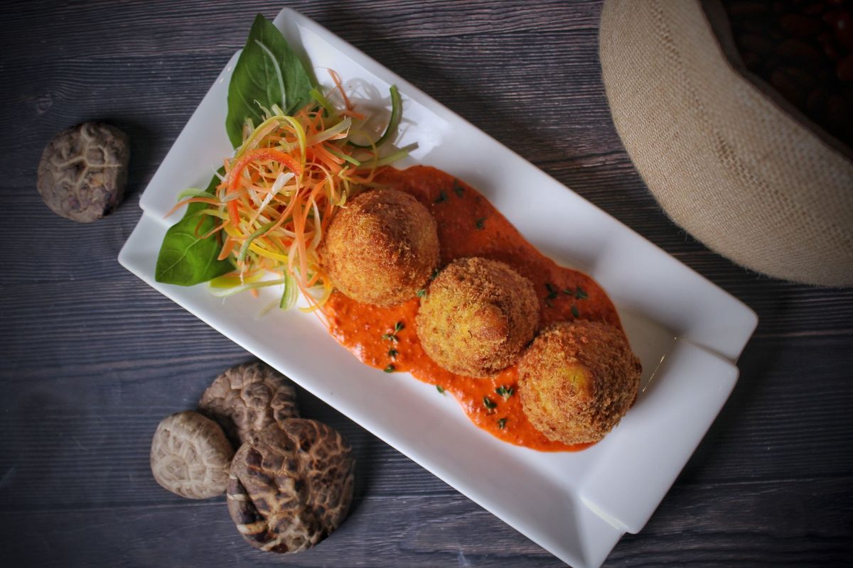 Golden Italian arancini fried rice balls served with tomato sauce and vegetables