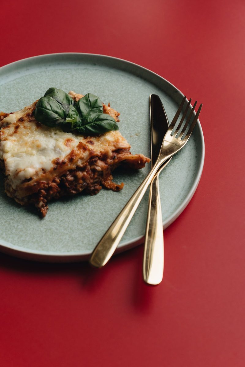 Finished basic lasagna slice with layered pasta, cheese, tomato sauce, and basil garnish
