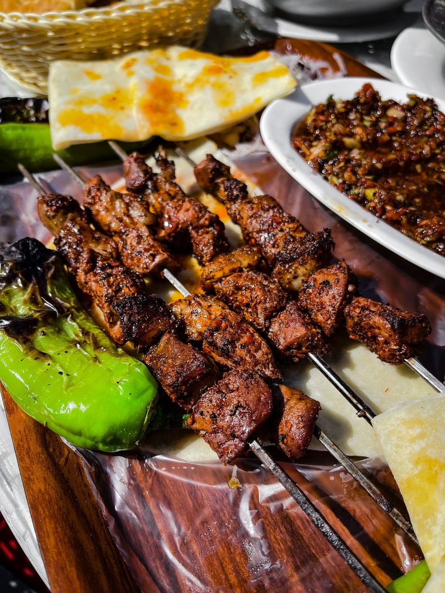 Finished beef skewers served with sliced bread and peppers