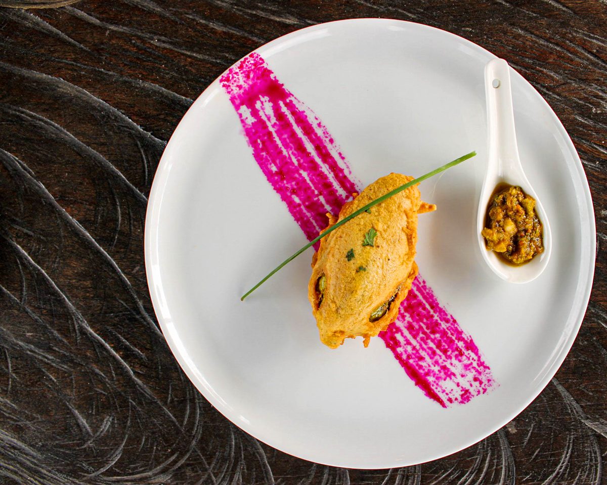 Finished South Indian bonda vegetable fritters served on a plate with onions and green chilies