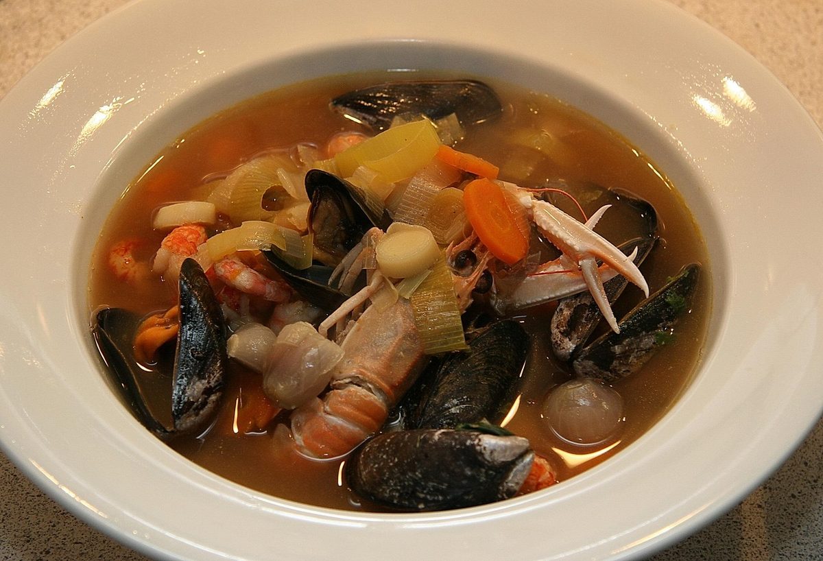 Bowl of bouillabaisse, a Provençal French seafood soup with mussels, shrimp, fish, vegetables, and clear broth.