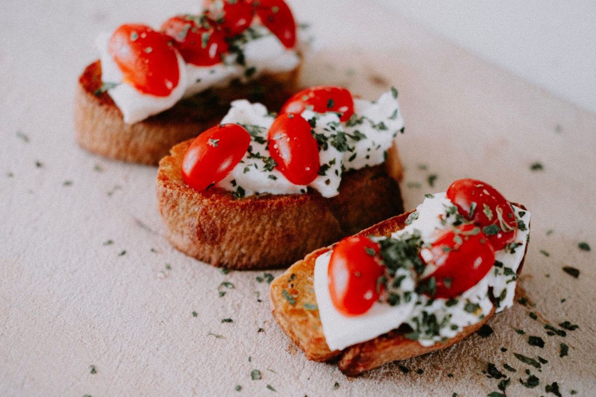 Finished Italian bruschetta topped with cherry tomatoes, cream cheese, and herbs on toasted bread