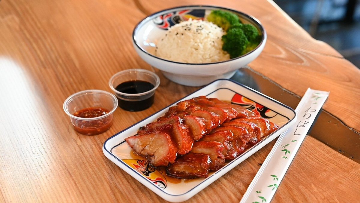 A plate of sliced char siu Chinese roast pork with rice, broccoli, and sauce.