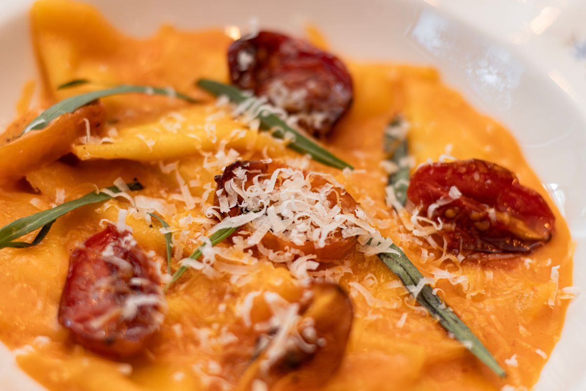 Finished cheese ravioli served with tomato garnish and grated Parmesan