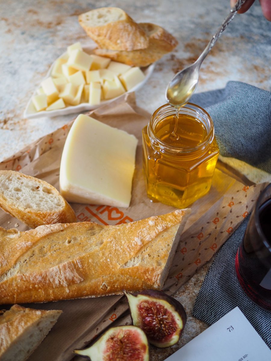 Sliced baguette arranged with cheese, figs, and honey on a rustic surface.