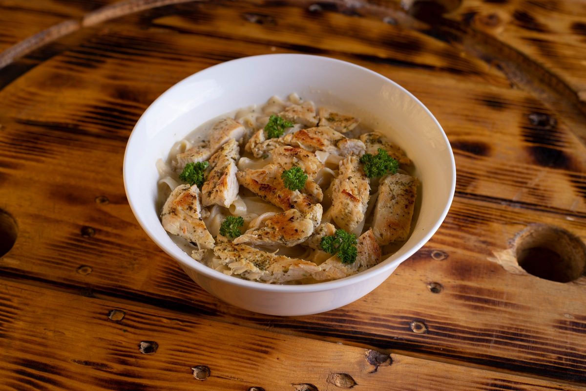 Finished chicken bacon broccoli Alfredo spaghetti in a white bowl