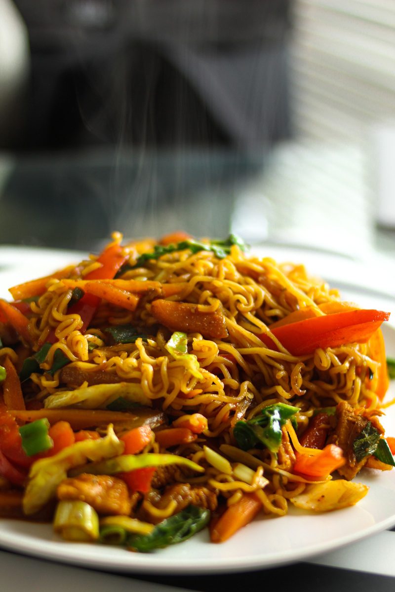 Finished Chow Mein noodles with mixed vegetables served on a white plate