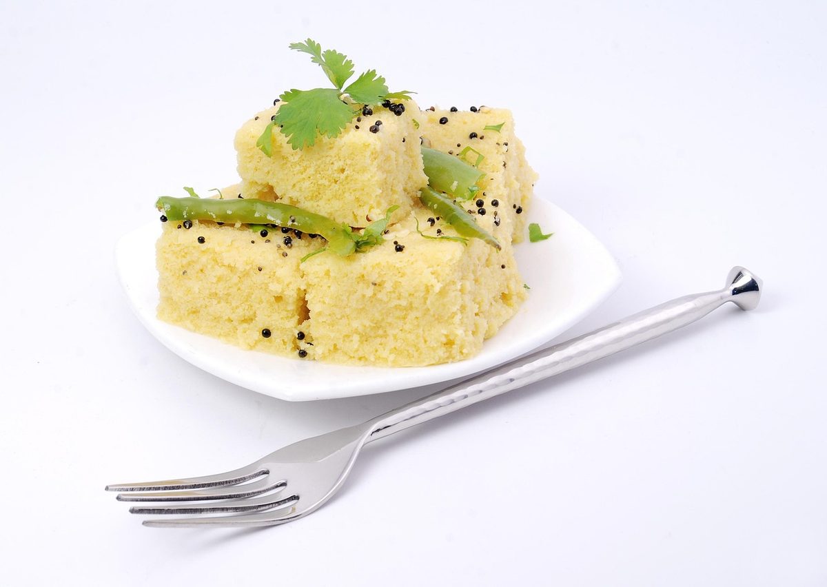 Finished steamed dhokla pieces, a soft savory Indian cake, served on a plate