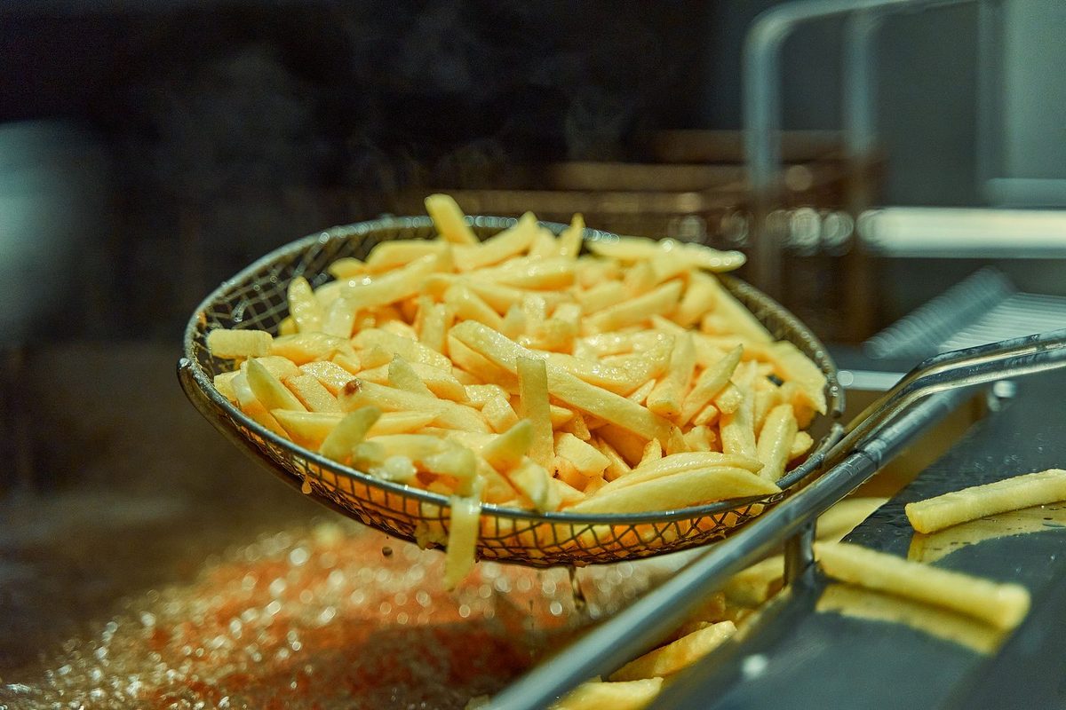 Crispy golden French fries piled in a serving container, freshly fried and ready to eat.