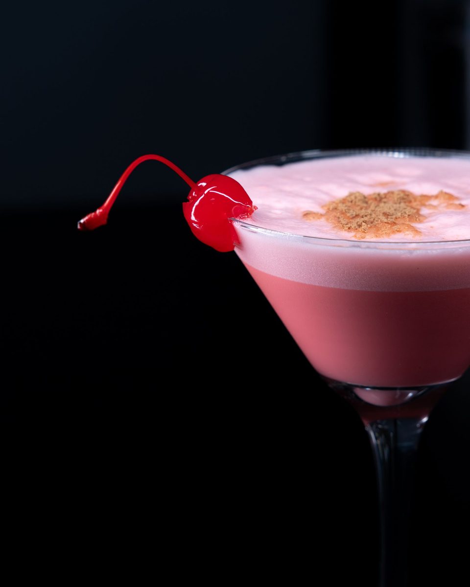 Finished French Martini, a frothy pink cocktail in a martini glass garnished with a maraschino cherry