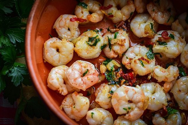 Finished Gambas al Ajillo-style garlic shrimp in a terracotta dish, sautéed with olive oil, garlic, parsley, and red chile