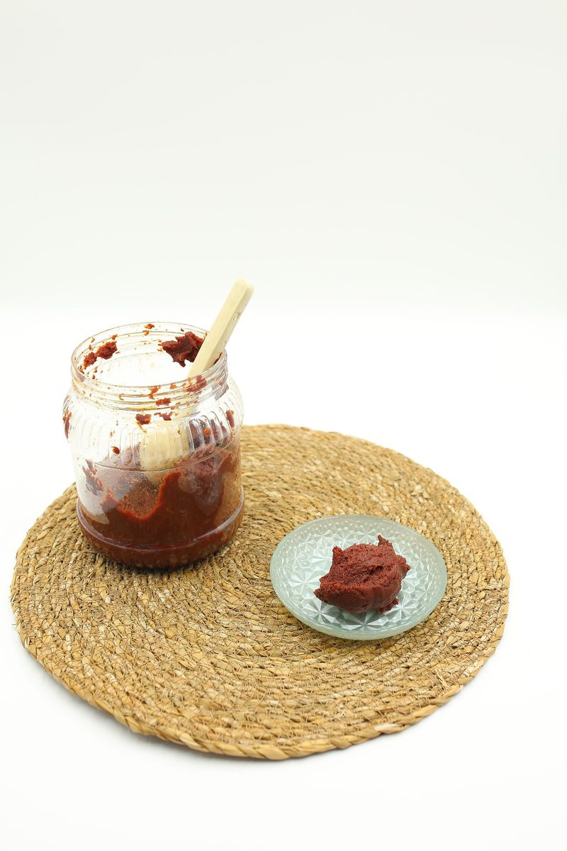 Gochujang (imitation), a finished Korean red chili paste in a jar with a small serving plate