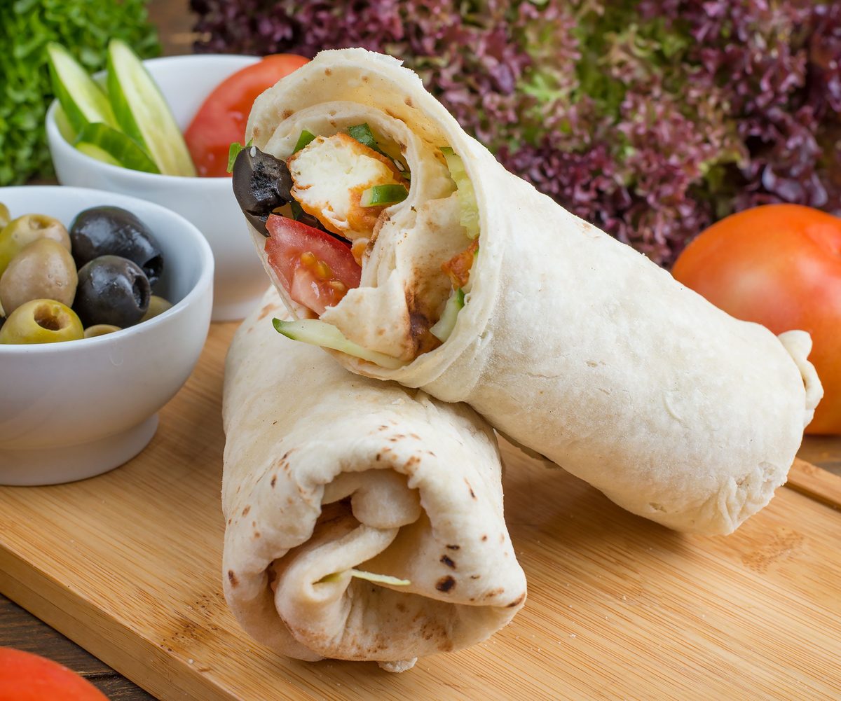 Finished Greek chicken wraps with chicken, vegetables, and feta-style filling in flatbread