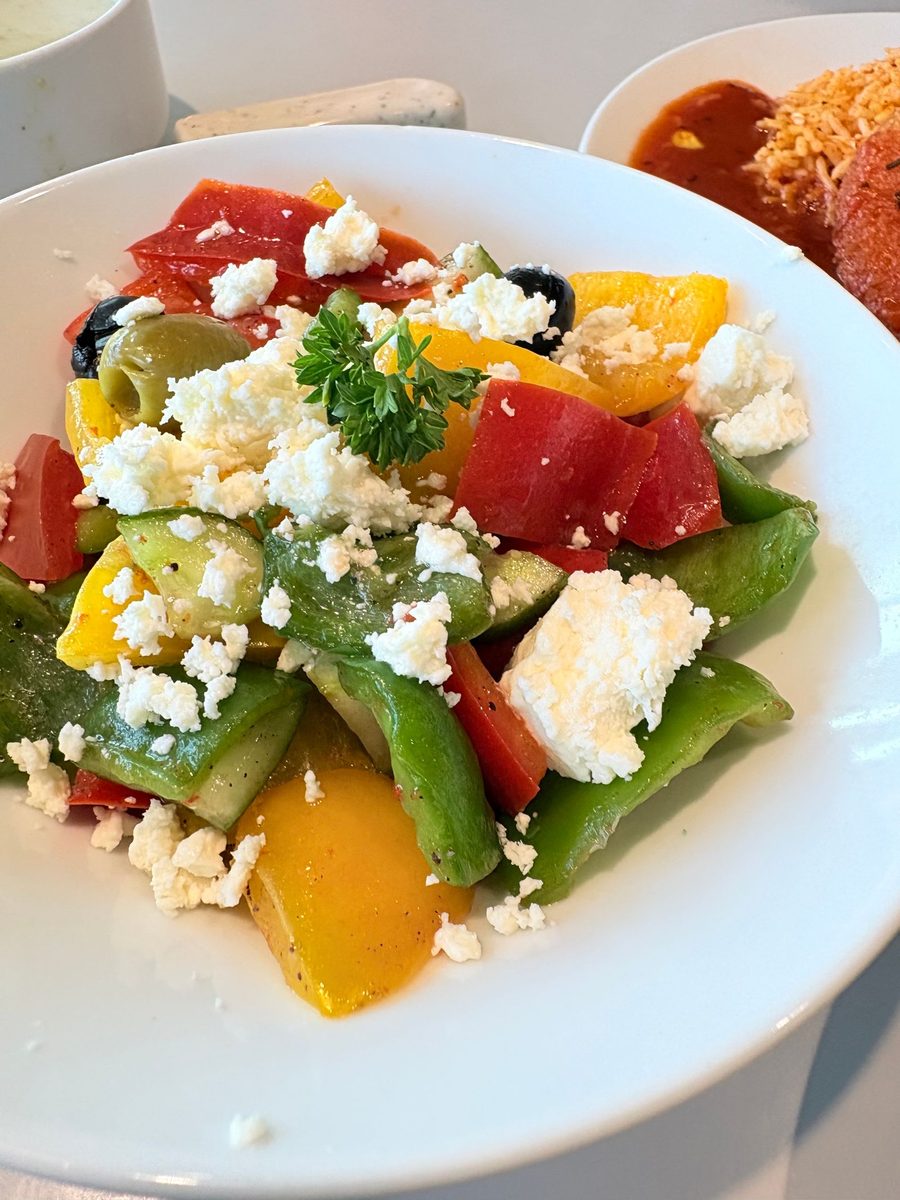 Finished Greek salad with tomatoes, cucumbers, bell peppers, olives, feta, and herbs