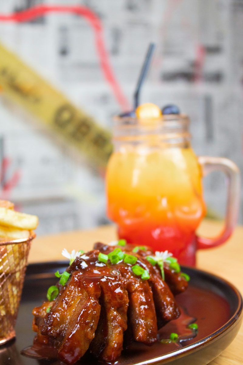 Close-up of glossy glazed pork ribs sprinkled with sesame seeds and garnished with dill on a plate.