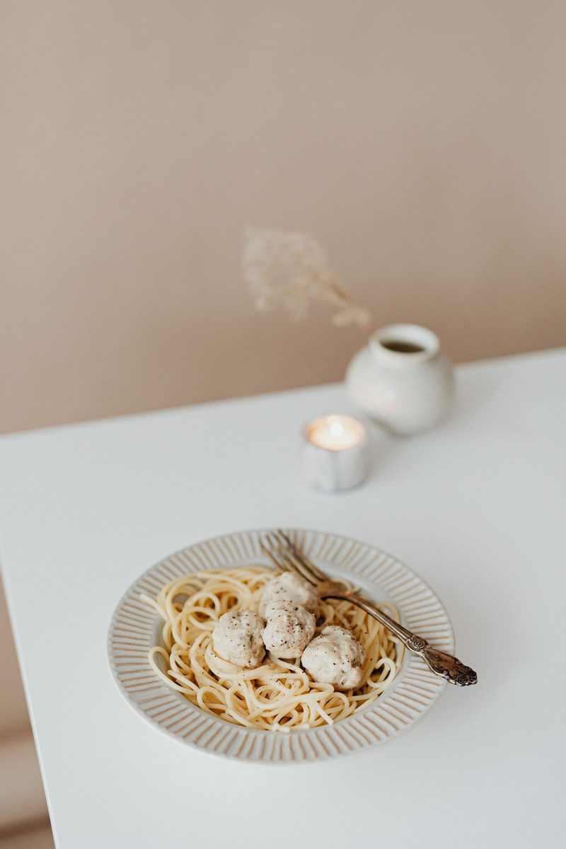 Plate of pasta with meatballs served on a white table setting