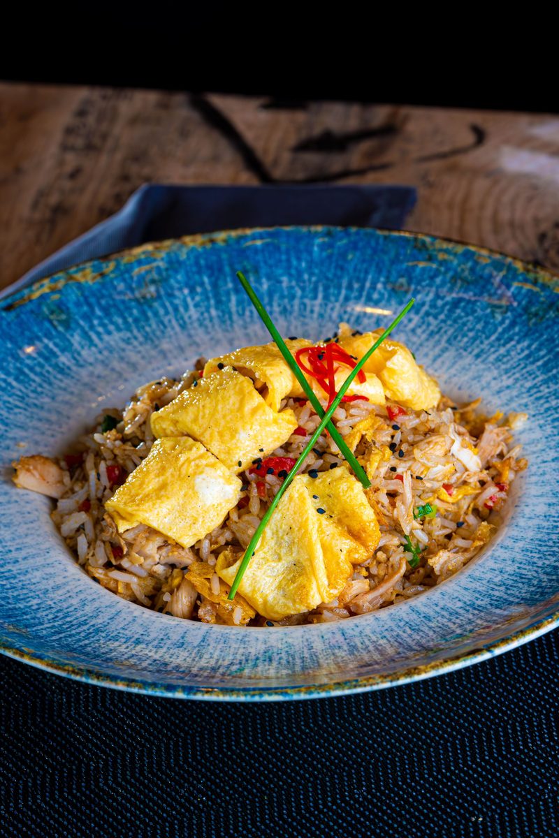Khao Pad Gai Thai chicken fried rice topped with sliced omelette and garnished with herbs