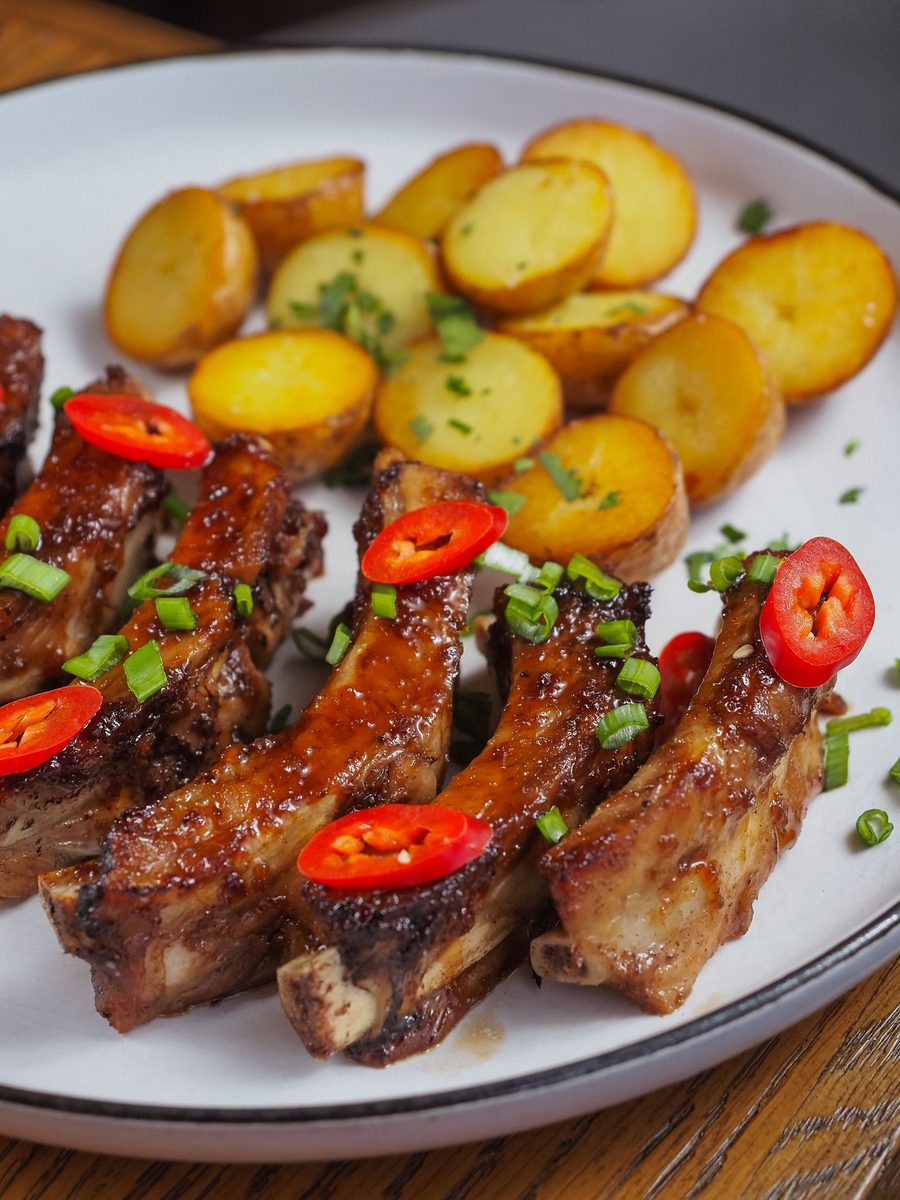 Finished Korean short ribs with roasted meat, red chilies, and crispy potatoes on a plate