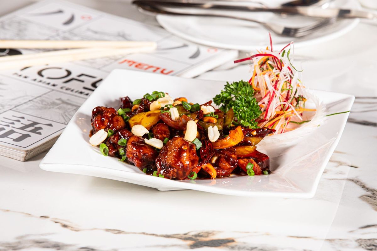 Finished Kung Pao Chicken with chicken pieces, peanuts, peppers, and scallions on a white plate