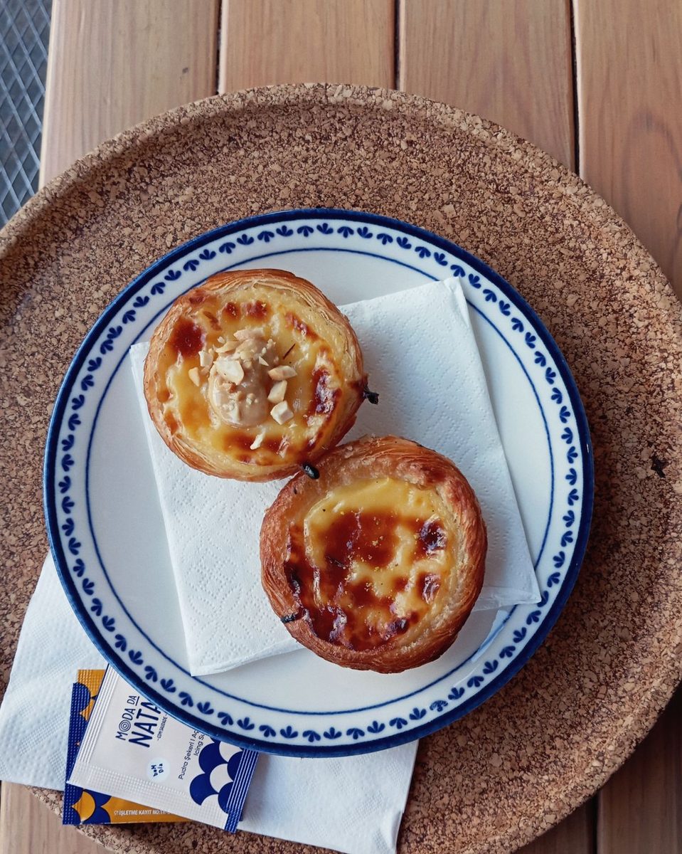 Golden-brown Portuguese custard tarts (Pastéis de Nata) arranged on a white plate.