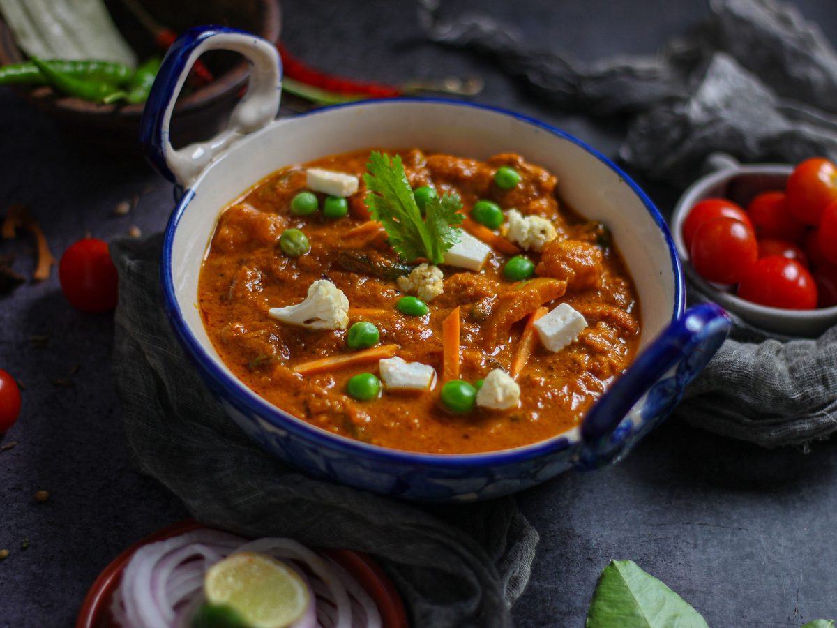 Finished Matar Paneer curry with paneer cubes and green peas in a blue ceramic bowl