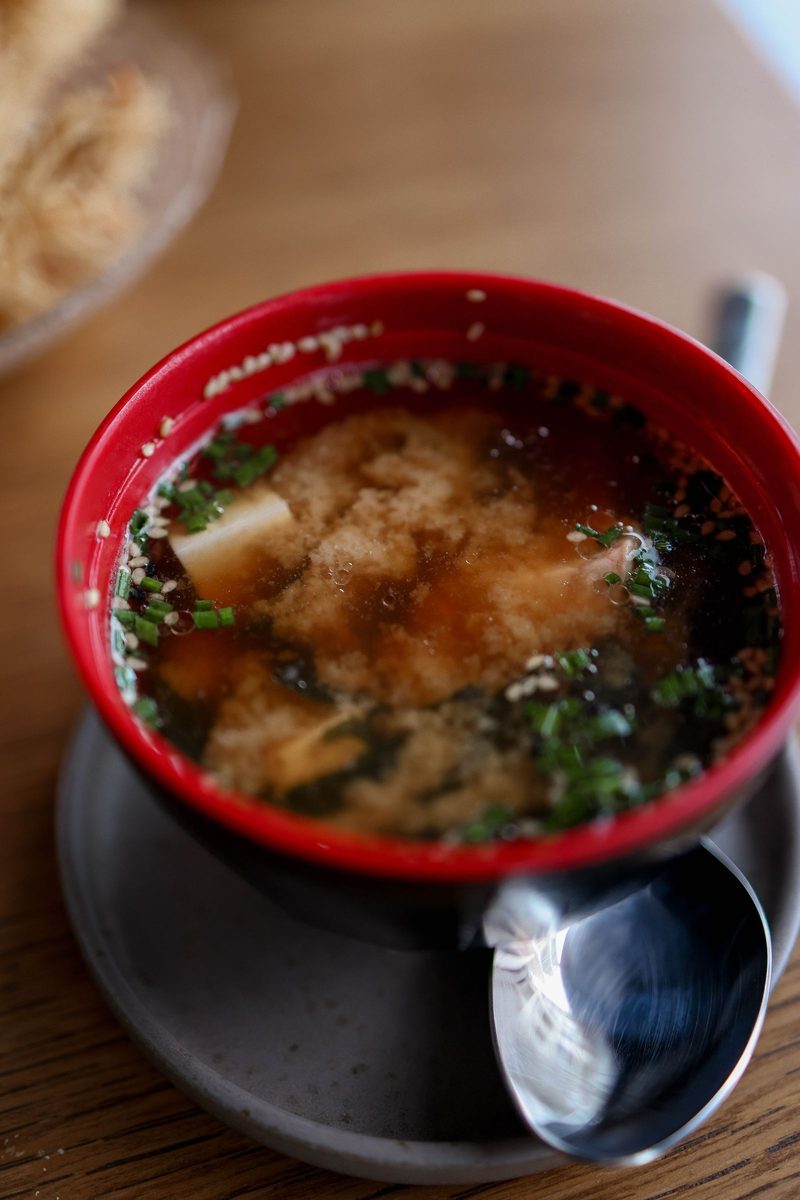 Traditional Japanese miso soup with tofu and green onions in a red bowl