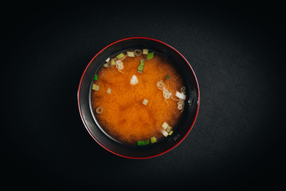 Finished miso soup with chopped green onions in a black bowl