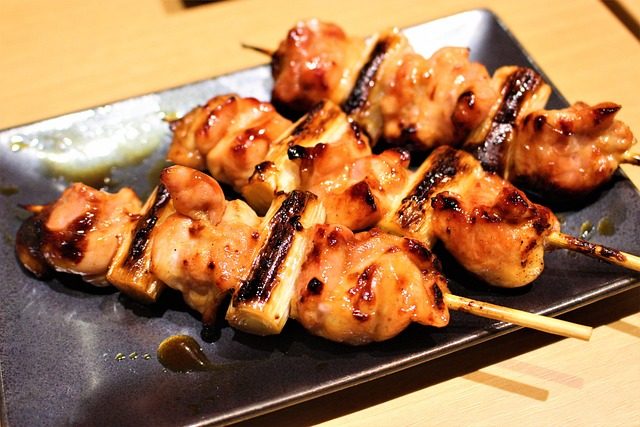Finished teriyaki-glazed skewers with grilled pineapple pieces on a black plate.