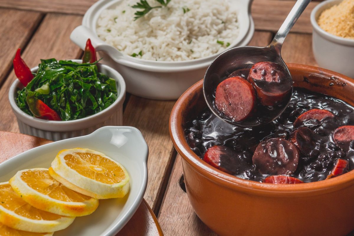 Finished Portuguese feijoada bean-and-meat stew served with rice, greens, and orange slices