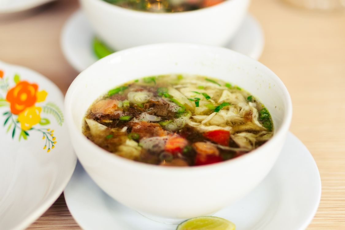A bowl of minestrone soup with noodles and vegetables.