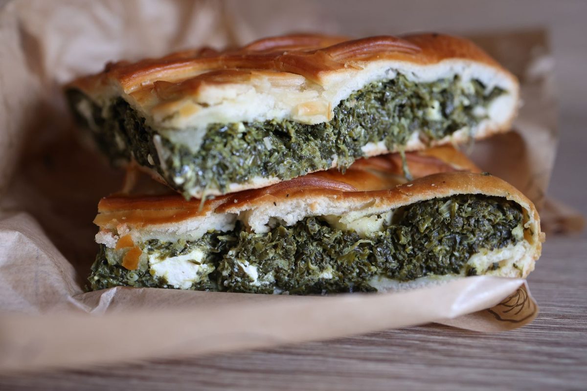 Close-up of golden spinach-and-feta spanakopita slices arranged on parchment paper.