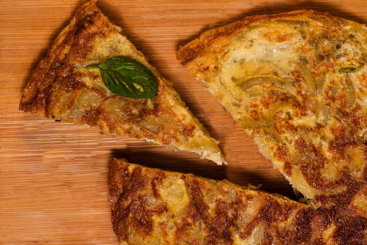 Finished Spanish potato omelette (tortilla española) slices on a wooden board