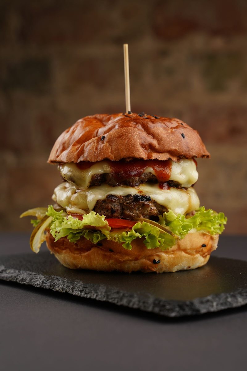 Finished spicy feta burger with a beef patty, melted cheese, lettuce, and tomato