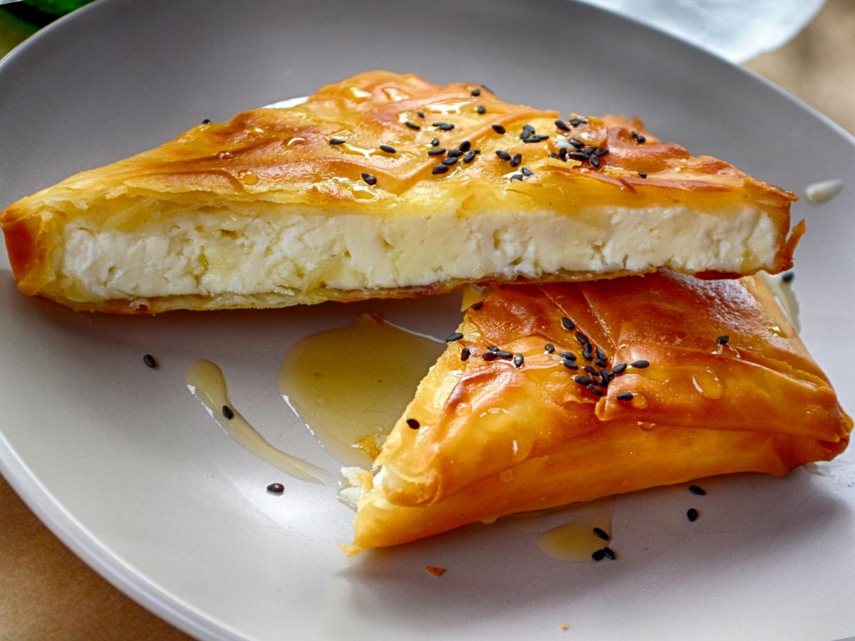 Finished Tyropita Greek cheese pie drizzled with honey and sprinkled with sesame seeds on a plate