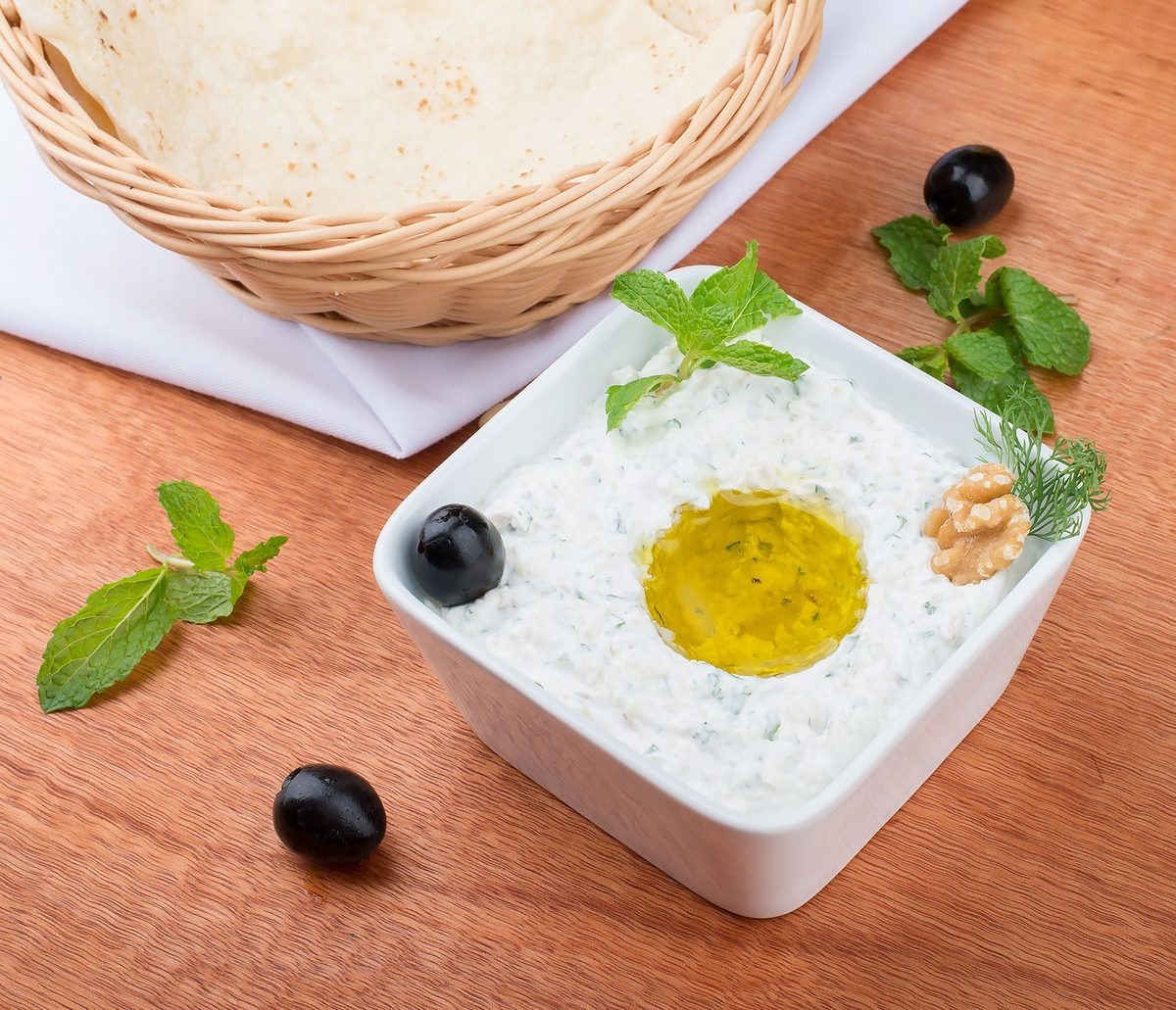 Finished tzatziki dip garnished with olive oil and herbs, served with bread